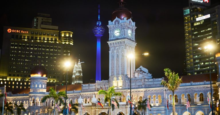 Illuminated Sultan Abdul Samad Building at night with Kuala Lumpur skyline and KL Tower in the background