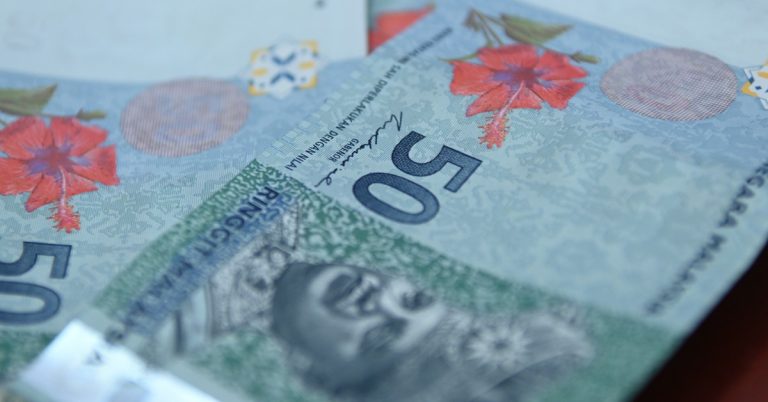 Close-up of Malaysian ringgit banknotes showing RM50 bills with security features and floral design