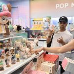 Shoppers browsing collectible designer toys at a Pop Mart store, selecting figurines and blind boxes
