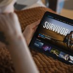 Woman watching a movie on a tablet at home, streaming content from an online entertainment platform