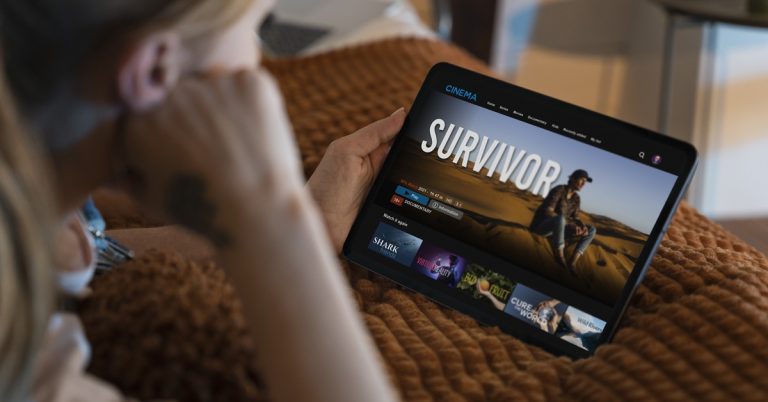 Woman watching a movie on a tablet at home, streaming content from an online entertainment platform