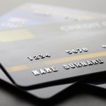 Close-up of stacked credit cards showing card numbers and names, representing payments, spending and personal finance