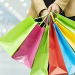 Person holding colorful shopping bags inside a shopping mall, representing retail shopping, sales, and consumer spending