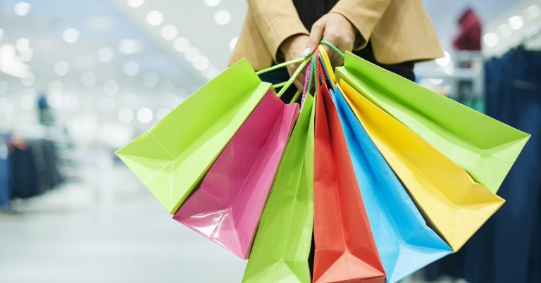 Person holding colorful shopping bags inside a shopping mall, representing retail shopping, sales, and consumer spending