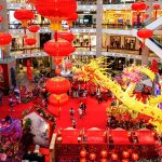 Shopping mall decorated for Chinese New Year with red lanterns, golden dragon display, festive crowd, and vibrant holiday atmosphere