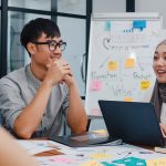 Young professionals discussing ideas in a business meeting with laptops and notes during a creative brainstorming session in office