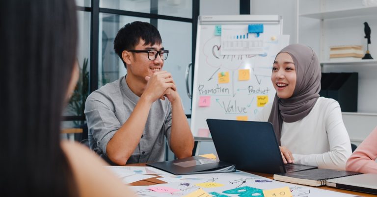 Young professionals discussing ideas in a business meeting with laptops and notes during a creative brainstorming session in office