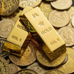 Gold bars marked 999.9 purity placed on assorted coins, symbolising wealth, precious metals investment and financial assets