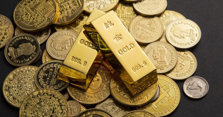 Gold bars marked 999.9 purity placed on assorted coins, symbolising wealth, precious metals investment and financial assets