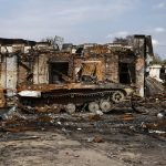 Destroyed buildings and burnt military vehicle in war-torn city, aftermath of armed conflict and urban devastation