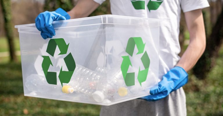 Person wearing gloves holding recycling bin with plastic bottles, promoting environmental cleanup and sustainable waste management