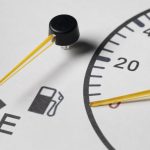 Close-up of car fuel gauge near empty with warning icon, indicating low fuel level and need to refuel soon