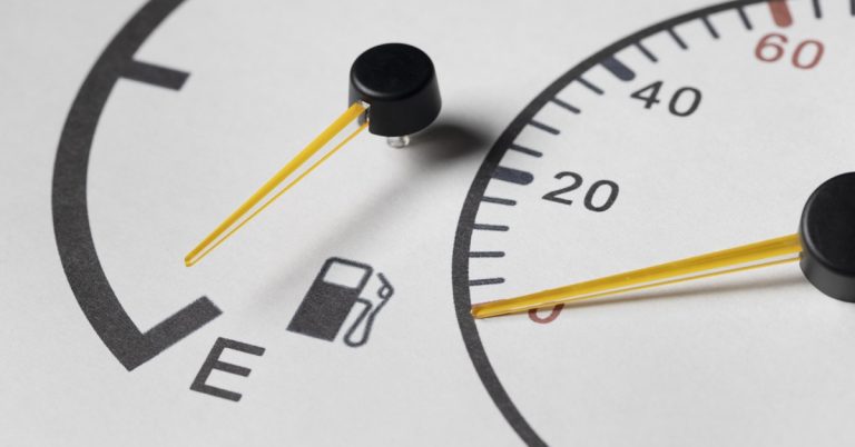 Close-up of car fuel gauge near empty with warning icon, indicating low fuel level and need to refuel soon
