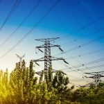 High voltage power lines and transmission towers at sunset, representing electricity grid infrastructure and energy distribution
