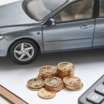 Car model with coins and calculator on desk, representing car loan, auto financing, budgeting and vehicle purchase costs