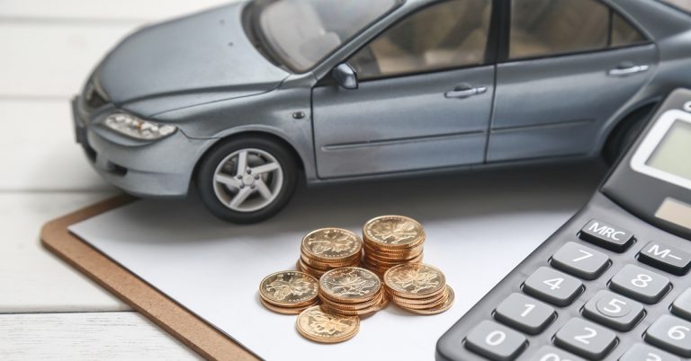 Car model with coins and calculator on desk, representing car loan, auto financing, budgeting and vehicle purchase costs