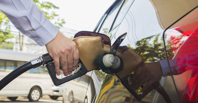 Person refueling car at gas station with fuel pump nozzle, representing petrol prices, transportation and vehicle costs