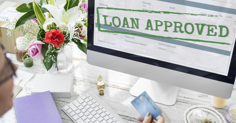 Loan approved application displayed on computer screen with customer holding credit card for personal financing approval