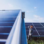 Man worker in the field by the solar panels