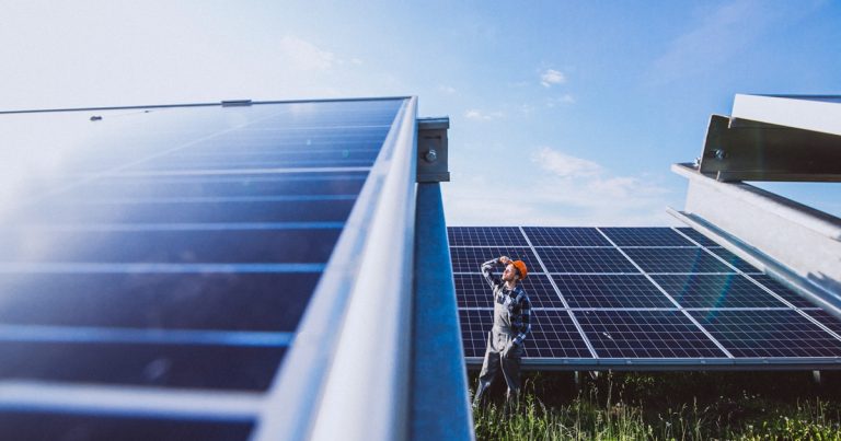 Man worker in the field by the solar panels
