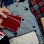 Woman hands with passports on the background open suitcase packed for travelling.